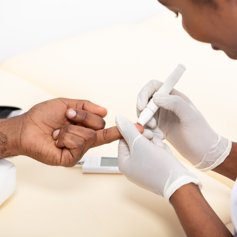 Close-up Of Female Doctor Checking Patient's Blood Sugar Level With Glucometer In Clinic