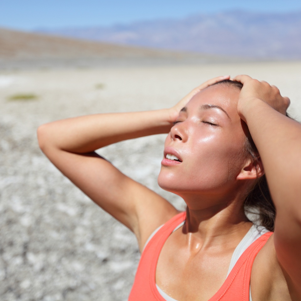 Desert woman thirsty dehydrated in Death Valley. Dehydration, overheating, thirst and heat stroke concept image with girl in desert nature.