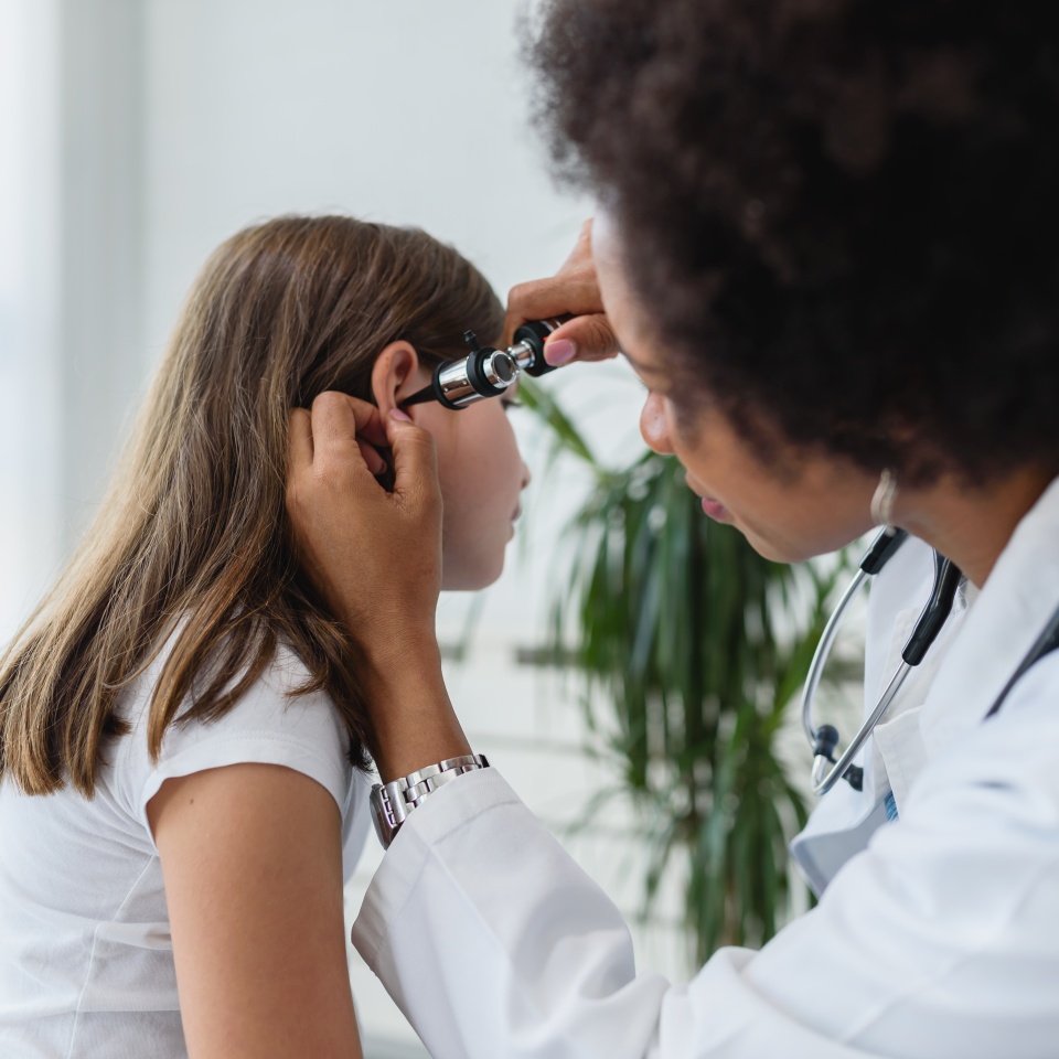 Woman afro american doctor general practitioner examining ear of a ill child. Ear infections.