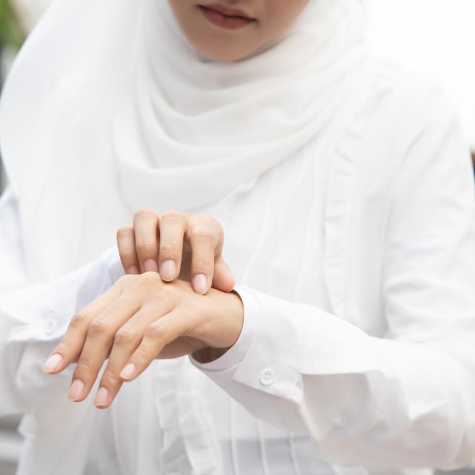Muslim woman scratching her hand skin; dry skin, allergic skin inflammation, body care, fungus inflammation, dermatology disease, eczema, rash, skin care concept; young adult Islamic woman model