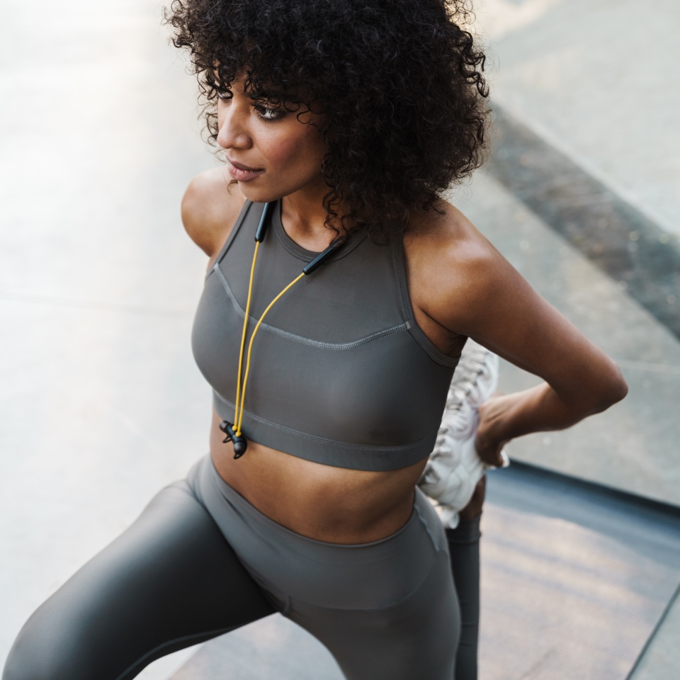 Image of african american sportswoman doing exercise while working out on sports ground