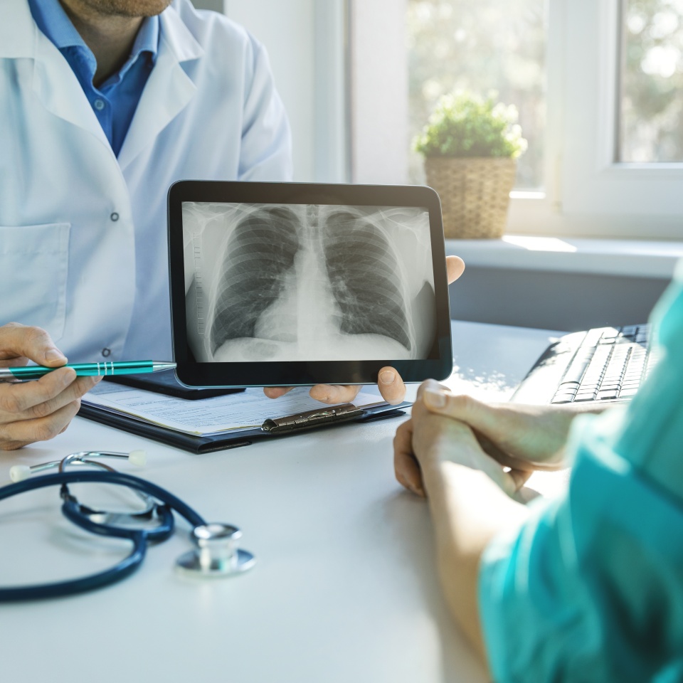 doctor and patient discuss chest x-ray results on digital tablet in clinics office