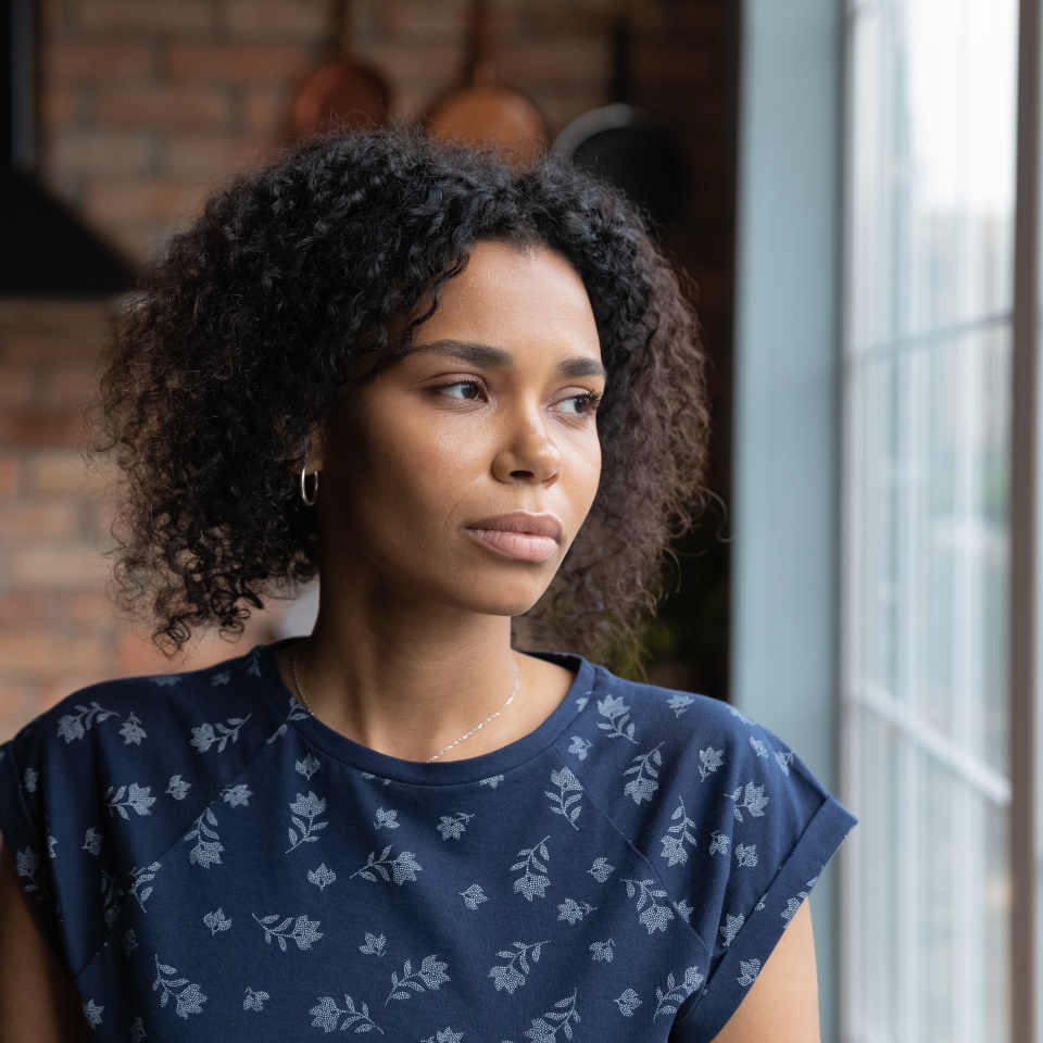 Close up upset African American woman looking to aside out window, standing at home, serious thoughtful young female lost in thoughts, thinking about problem, worried by break up with boyfriend