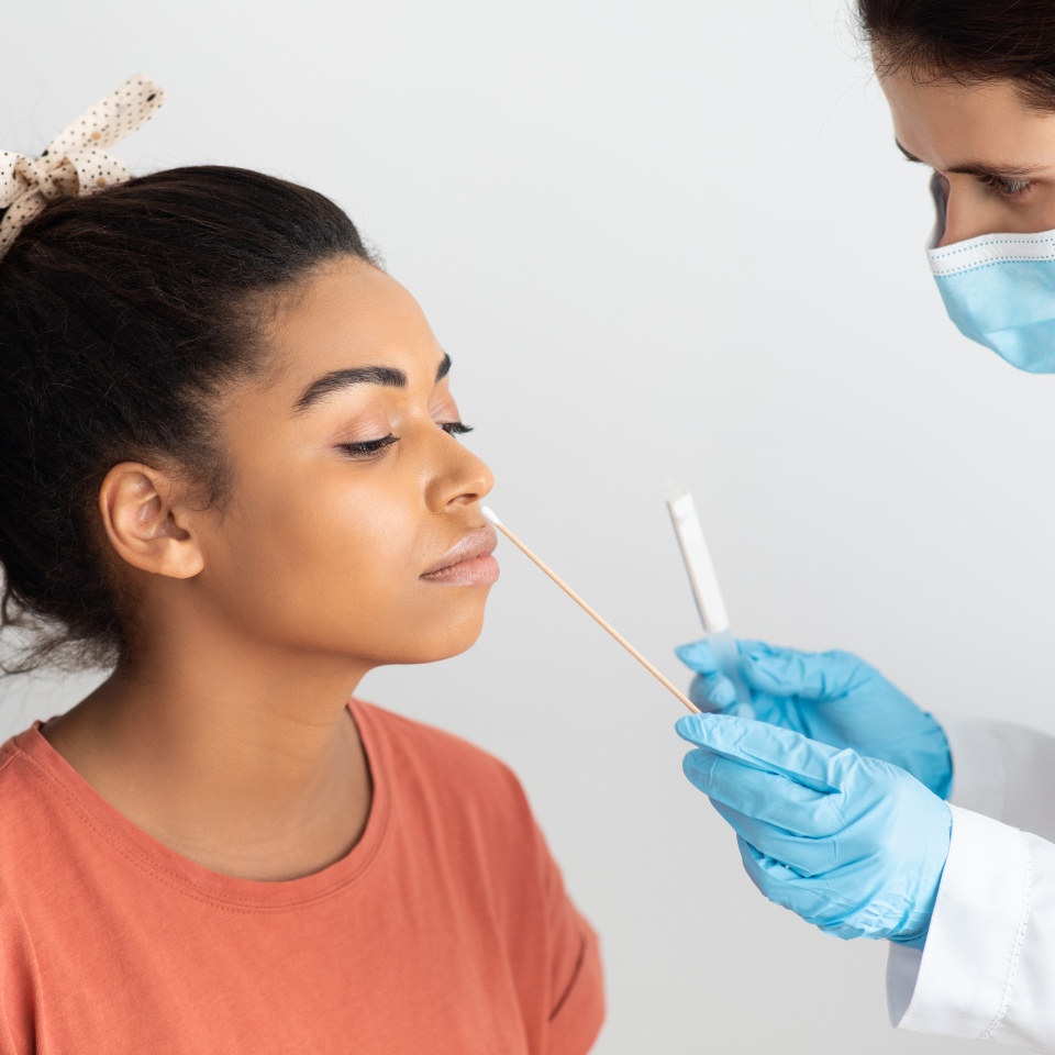 Coronavirus, COVID-19 pcr test concept. Doctor taking nasal swab for coronavirus sample test from potentially infected female patient african american woman at hospital, studio background, closeup