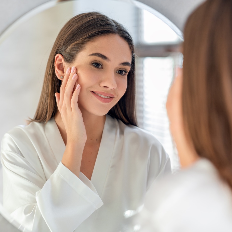 Natural Beauty. Portrait Of Attractive Young Female Smiling To Her Reflection In Mirror, Beautiful Millennial Woman Enjoying Her Appearance While Getting Ready In Bathroom, Selective Focus