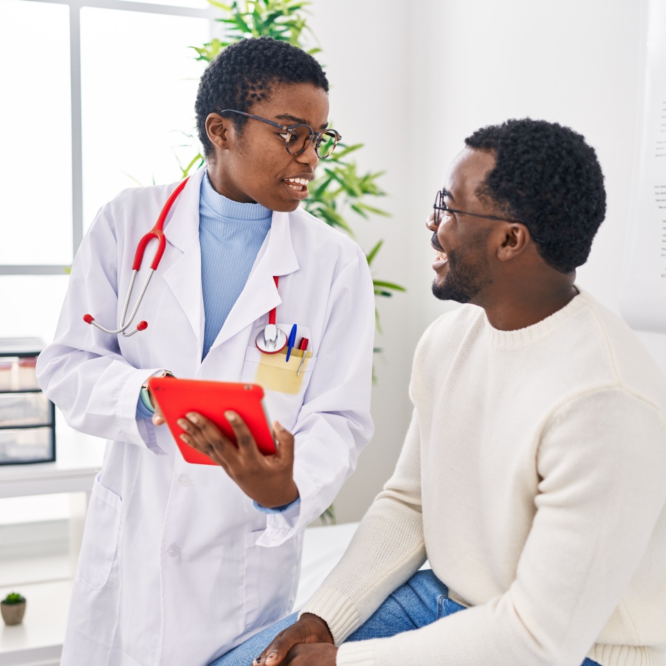 Man and woman doctor and patient having medical consultation using touchpad at clinic