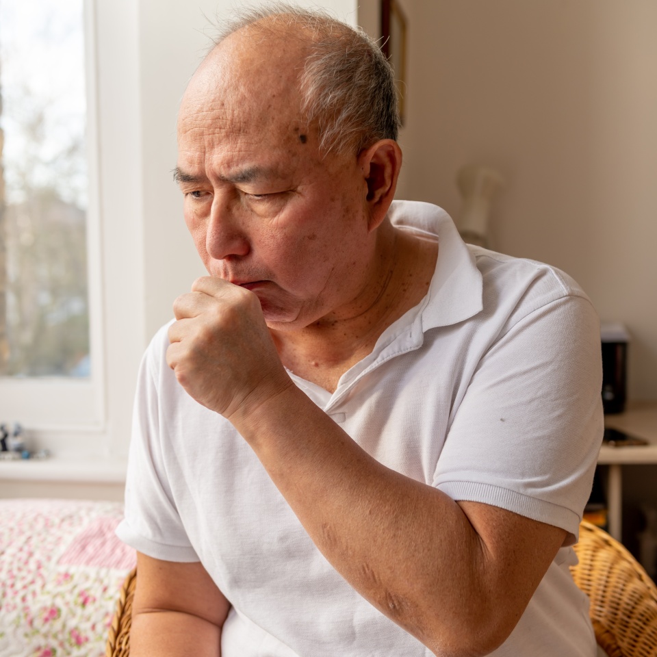 A elderly man coughing. Suffering the symptoms of Winter cold and flu.