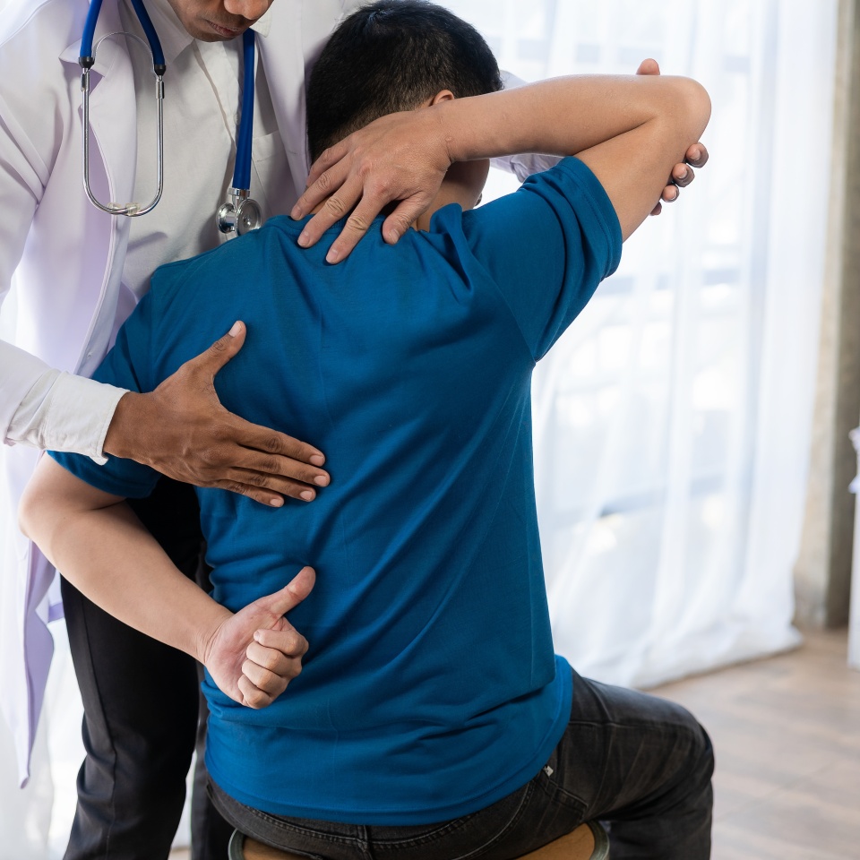 Young Asian man doing physiotherapy and seeking advice from muscle pain with shoulder, limbs in rehabilitation center.