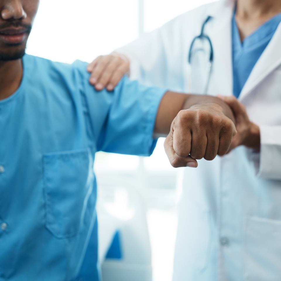 Doctor examining his patient arm in medical office while the patient sitting on hospital bed.