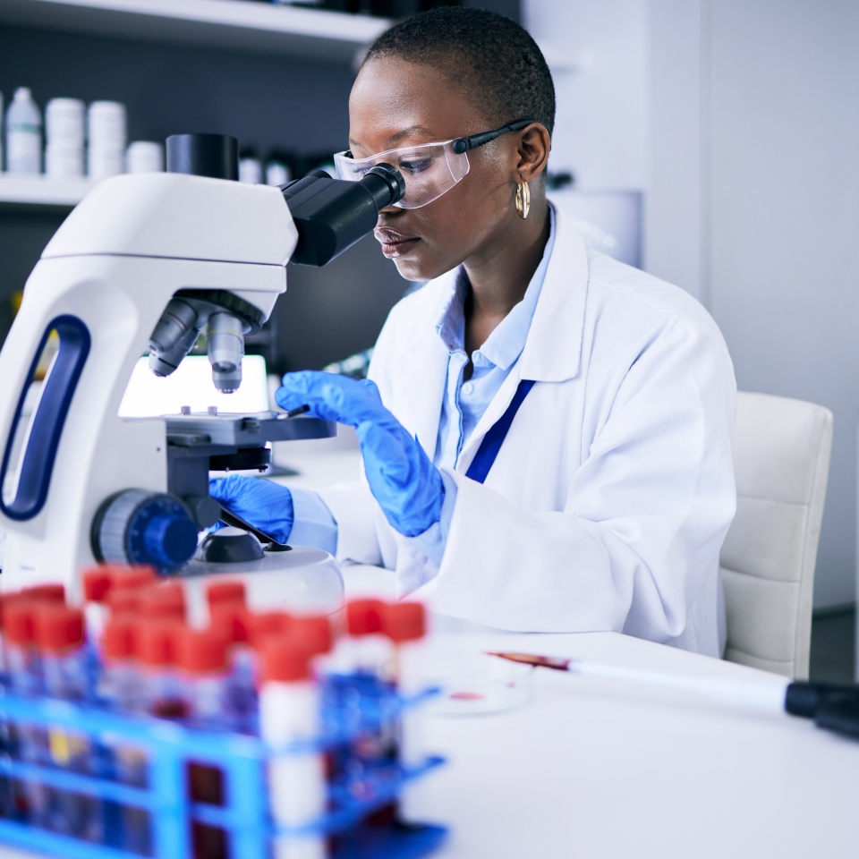 Science, laboratory and woman on microscope for blood test research, medical analysis and dna or virus tube. Biotechnology, healthcare and scientist, doctor or african person check for particles
