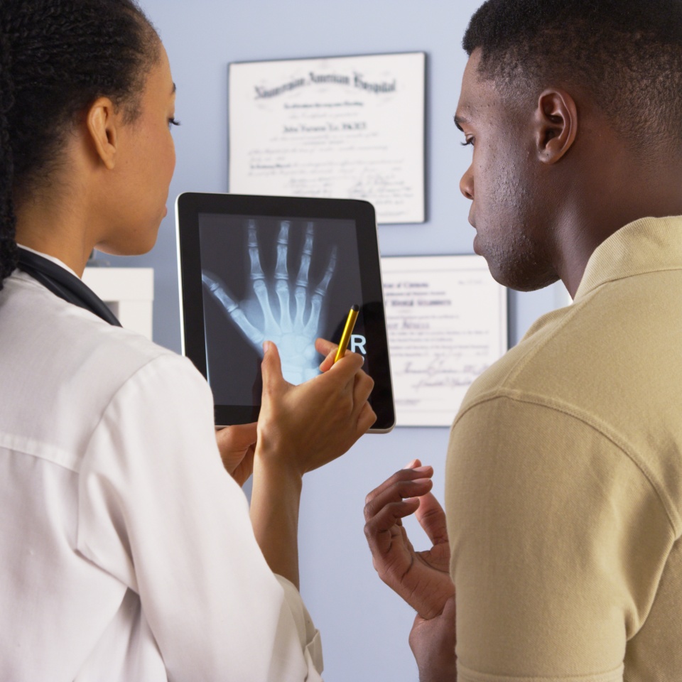 Black female doctor sharing hand x ray with patient on tablet