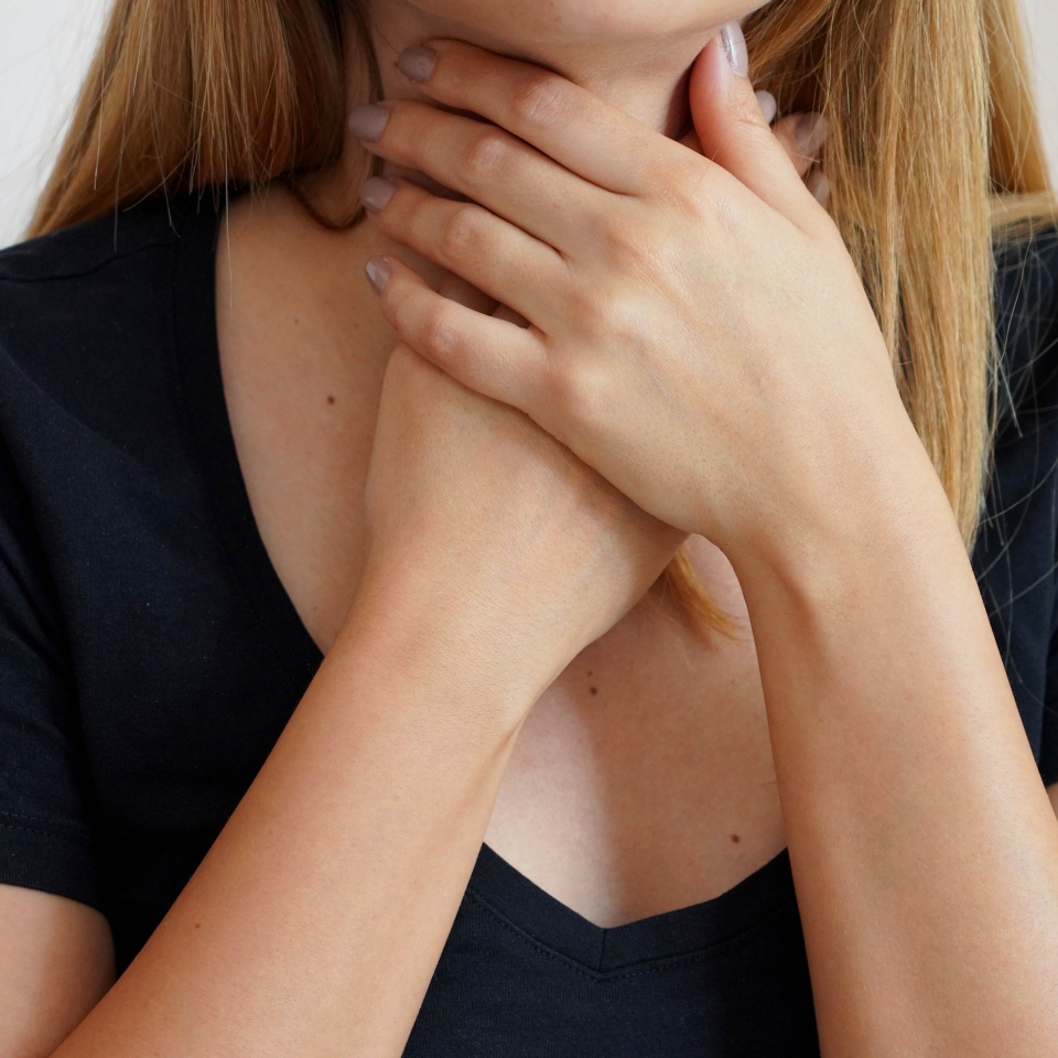 Sore Throat. Close-up of beautiful woman with hands on neck. Concept of sore throat, pharyngitis, laryngitis, thyroiditis, choking or dysphagia.