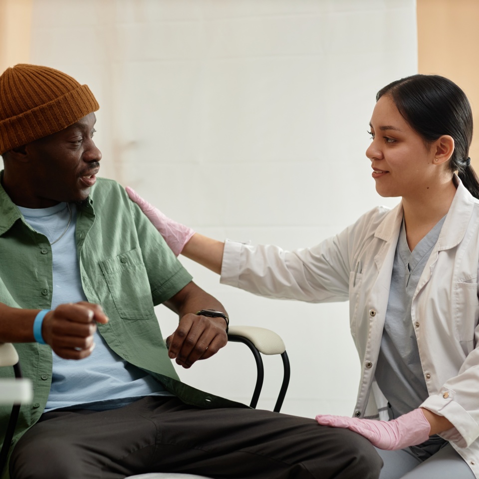 Side view portrait of smiling female doctor comforting patient receiving IV treatment in clinic