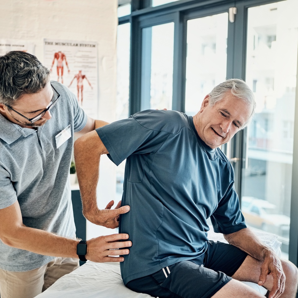 Physio therapist, chiropractor and senior man with back pain for rehabilitation, consulting and exercise. Healthcare, physical therapy and person and patient for medical service, wellness and support