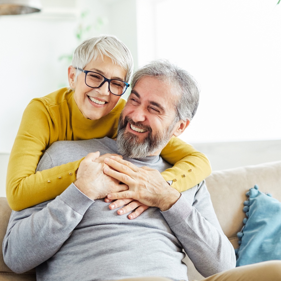 Portrait of a happy senior couple embracing hugging and having fun at home