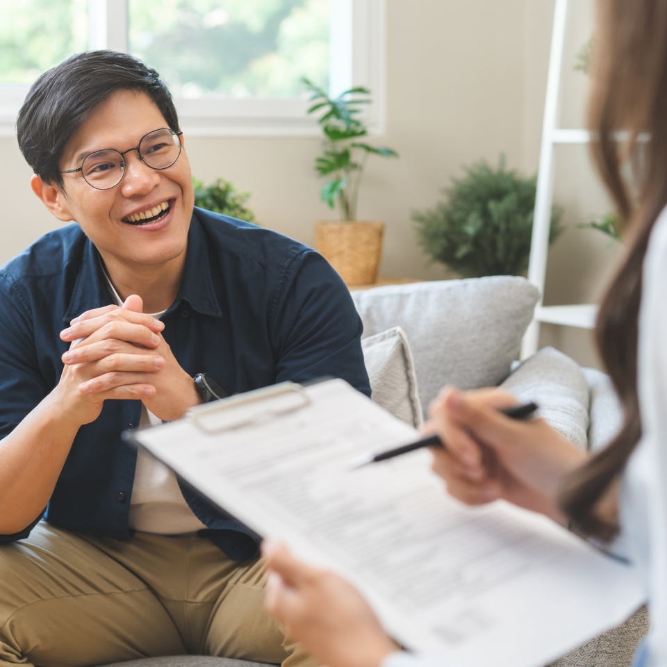Psychology, depression. smile asian young male, man patient mental sitting on couch, explained symptom with psychologist, psychiatrist while doctor woman taking notes at clinic. Encouraging, therapy.