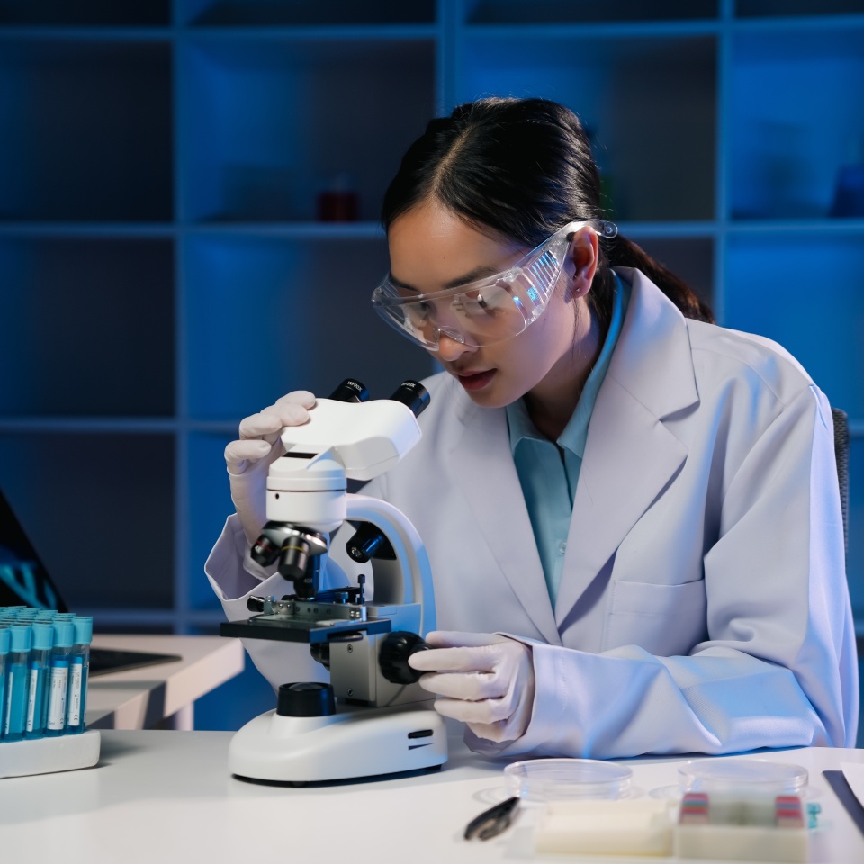 Scientist adjusting microscope, conducting research in a modern laboratory. The lab is equipped with advanced technology, reflecting the cutting edge nature of her work