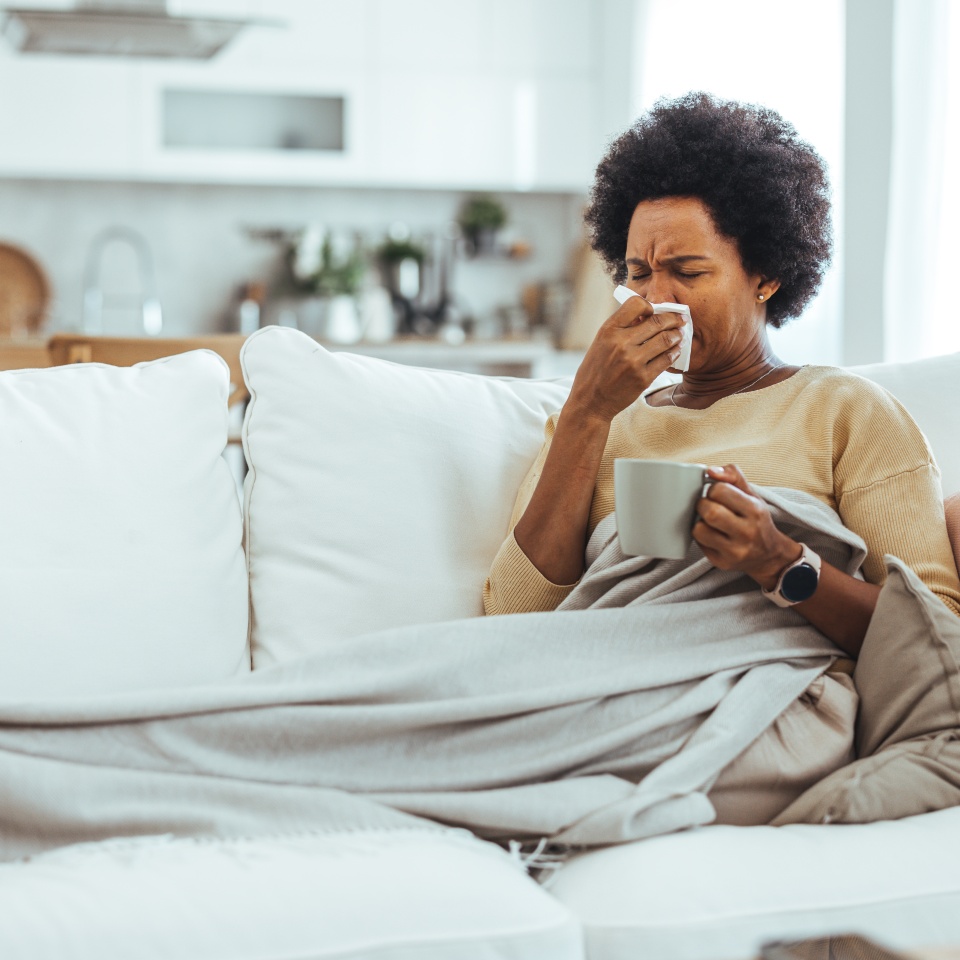 Woman with flu in bed, she use home medicine to handle sickness. Ill Woman Caught Cold, Feeling Sick And Sneezing In Paper Wipe. Closeup Of Beautiful Unhealthy Girl Covered In Blanket Wiping Nose.