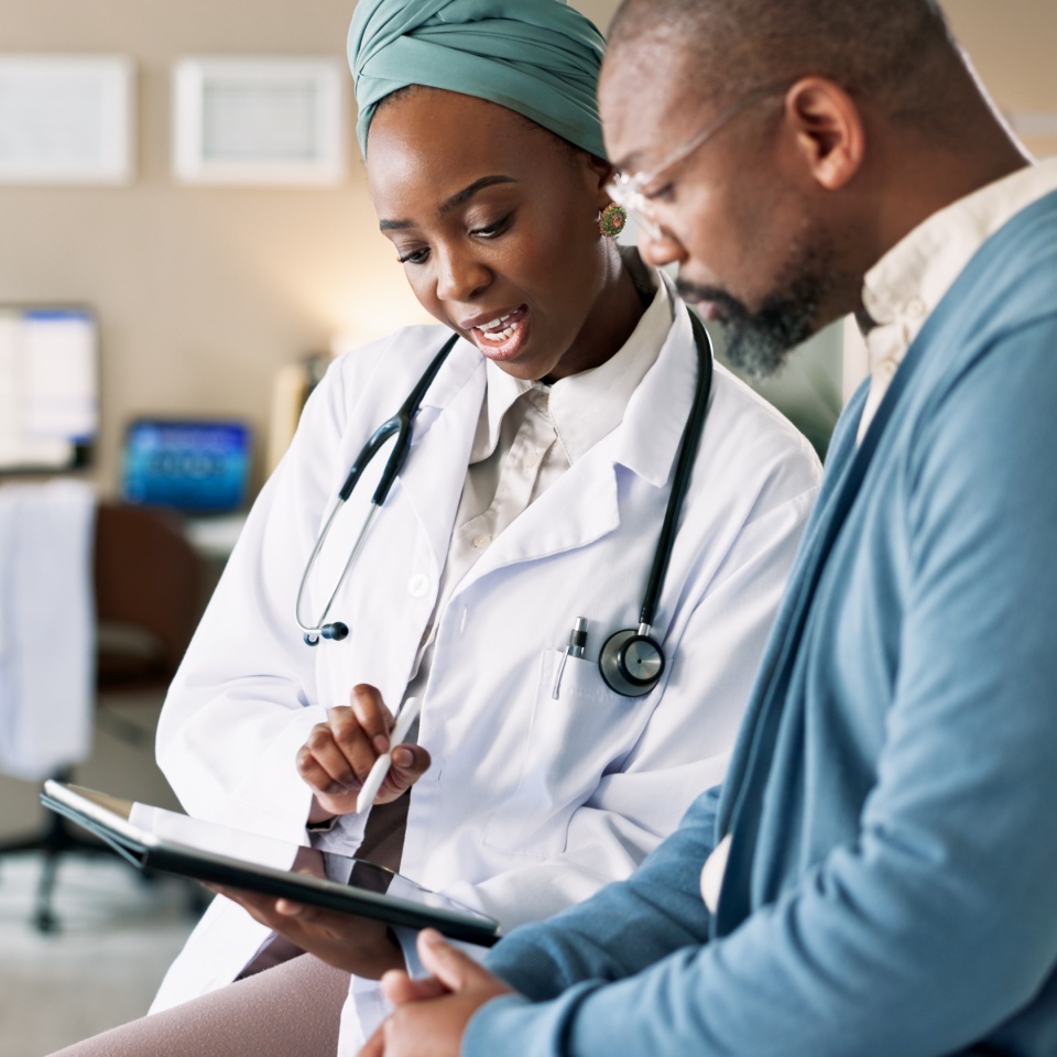 Tablet, patient and consultation with doctor for healthcare, insurance or exam results. African people, technology and medical professional explain treatment for wellness, checkup and help in clinic