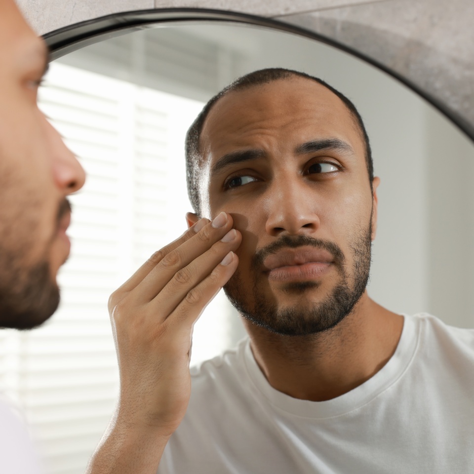 Worried man looking at mirror in bathroom