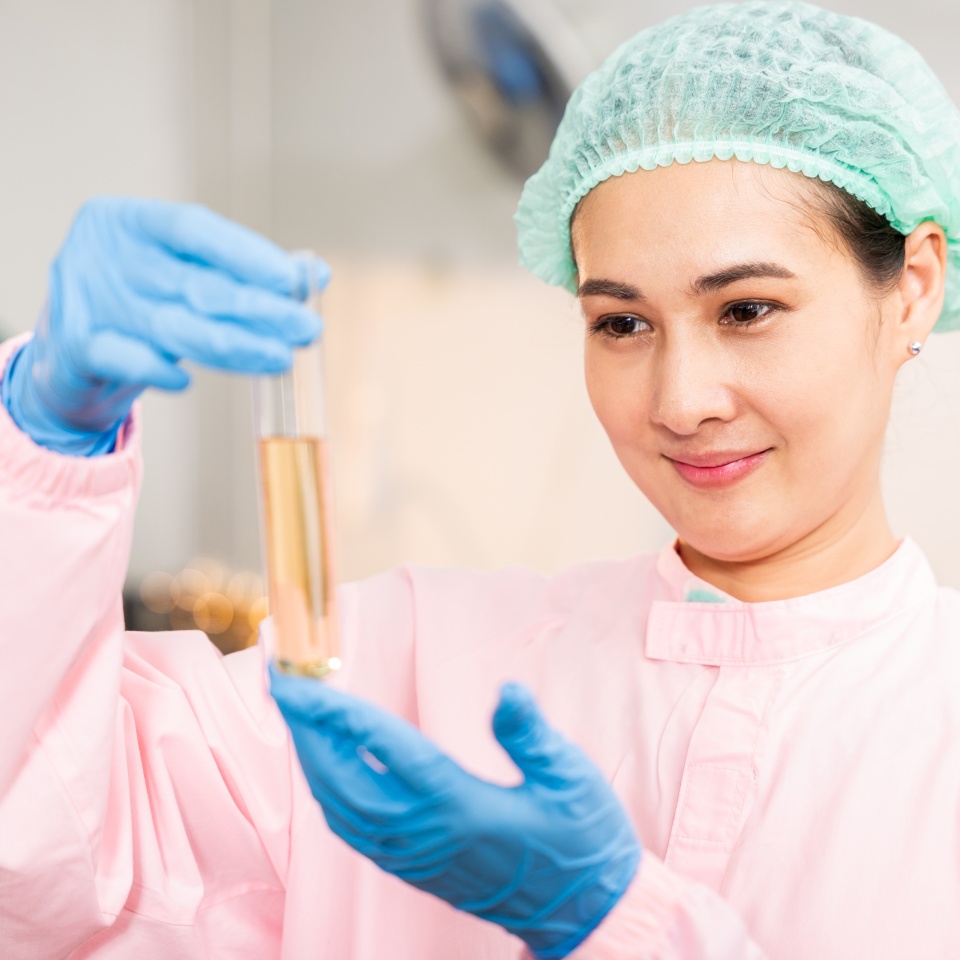 Juice beverage factory woman food engineer emphasizes food and beverage quality and safety testing employing test tubes to sample basil or chia seeds in bottled products in laboratory control.