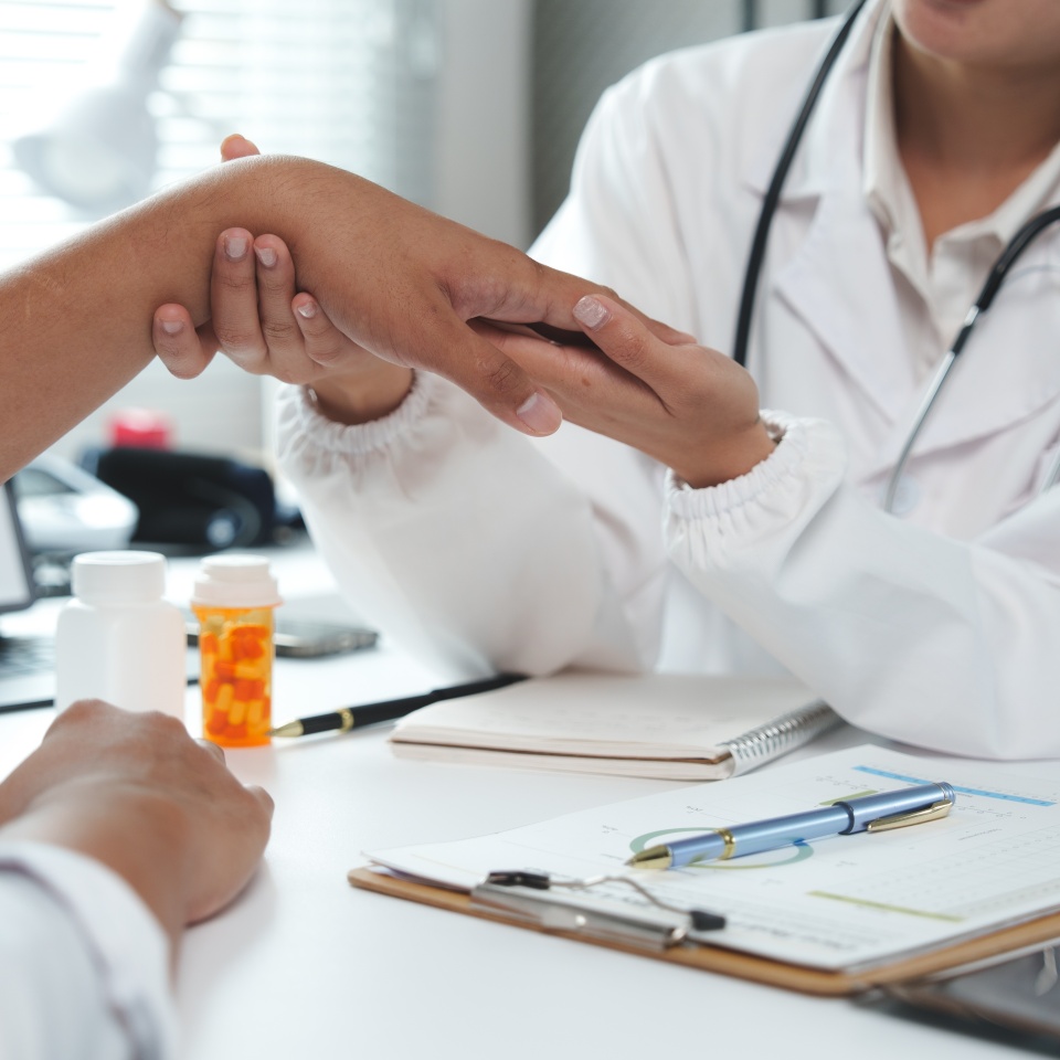 Female doctor examining wrist of a patient suffering from wrist pain in clinic or hospital