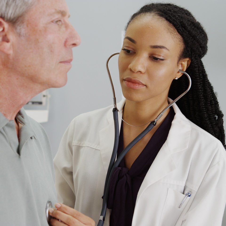 Black doctor listening to senior breathing