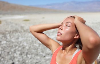 Desert woman thirsty dehydrated in Death Valley. Dehydration, overheating, thirst and heat stroke concept image with girl in desert nature.