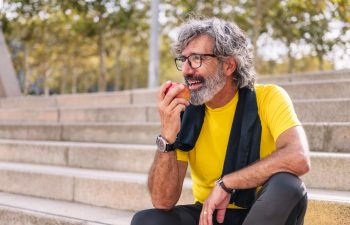 senior sports man rests eating an apple after a hard workout, concept of healthy and active lifestyle in the middle age, copy space for text