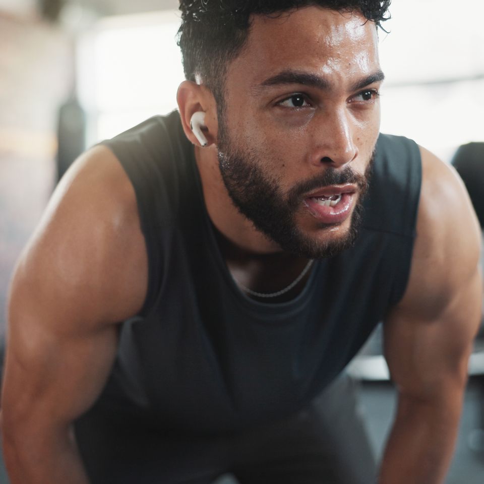 Athlete man sweating and tired in recovery after intense workout at a gym.